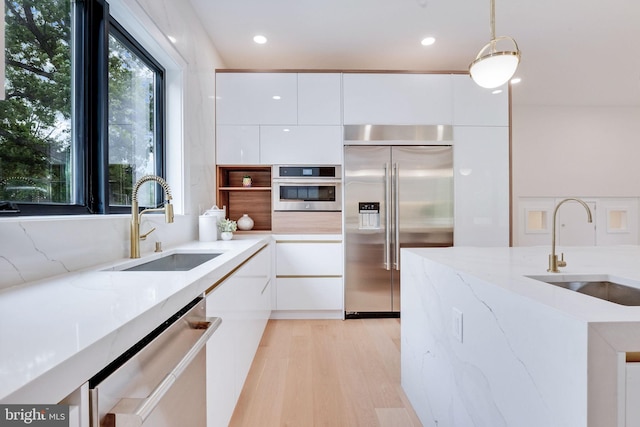 kitchen with sink, white cabinets, stainless steel appliances, and decorative light fixtures