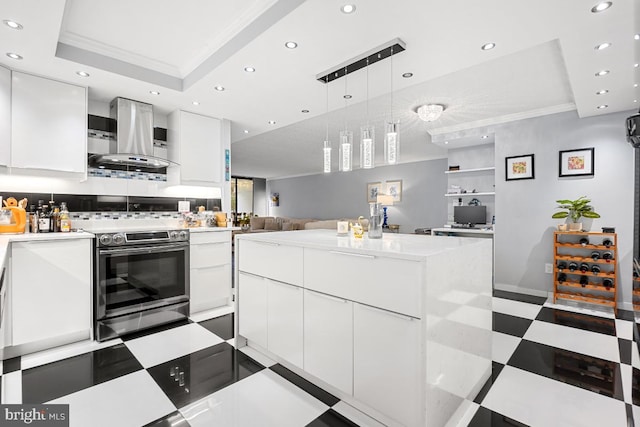 kitchen featuring crown molding, wall chimney range hood, white cabinets, a center island, and stainless steel range with electric cooktop