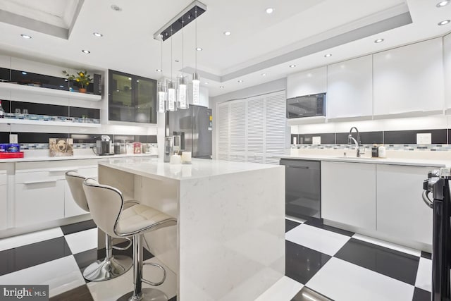 kitchen with a center island, hanging light fixtures, a tray ceiling, white cabinetry, and stainless steel appliances