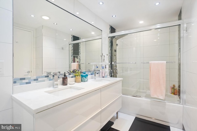 bathroom with decorative backsplash, vanity, and combined bath / shower with glass door