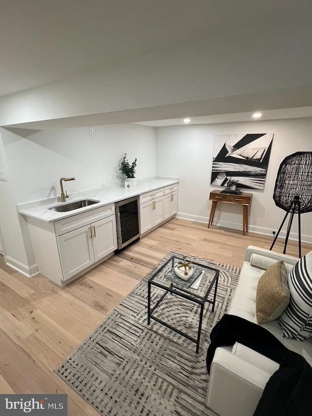 living room with sink, beverage cooler, and light hardwood / wood-style flooring