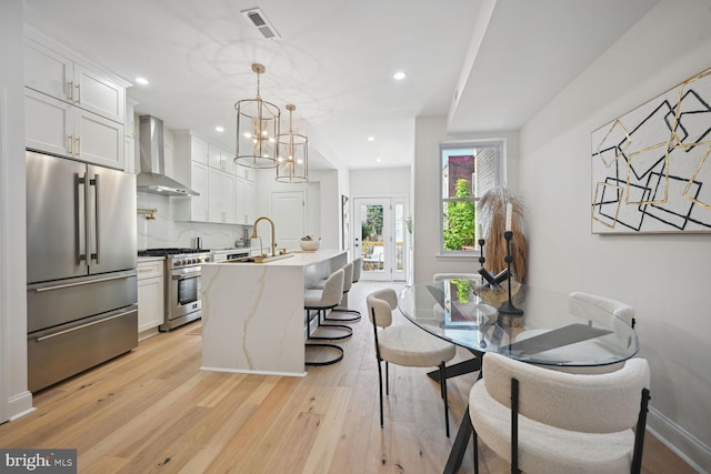 dining room featuring light wood-type flooring, sink, and an inviting chandelier