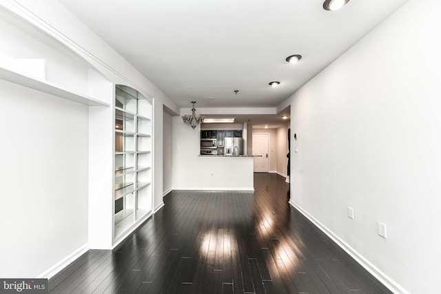 unfurnished living room featuring dark hardwood / wood-style floors and an inviting chandelier