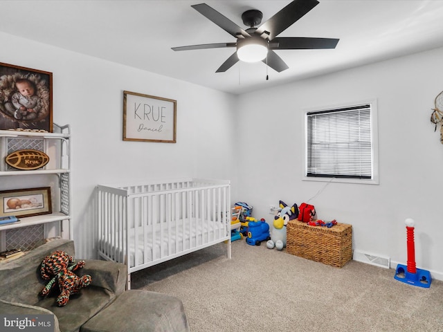 bedroom featuring a crib, carpet flooring, and ceiling fan