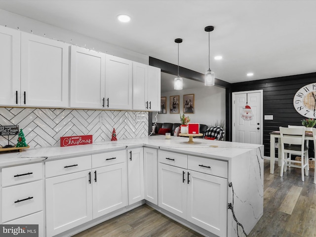 kitchen with kitchen peninsula, pendant lighting, white cabinetry, and wood-type flooring