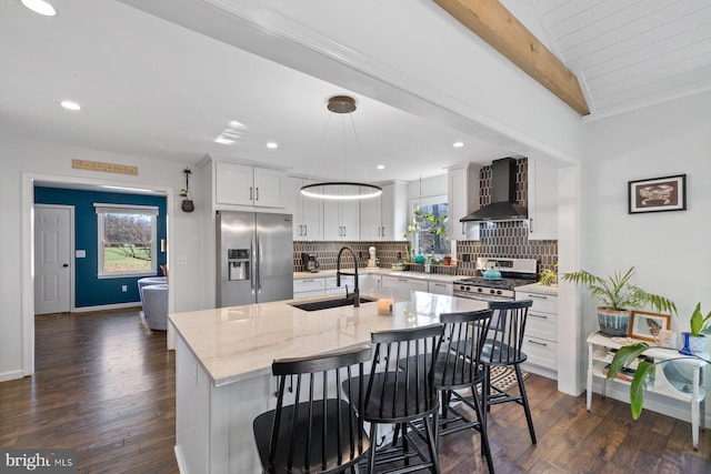 kitchen featuring appliances with stainless steel finishes, a healthy amount of sunlight, sink, wall chimney range hood, and dark hardwood / wood-style floors