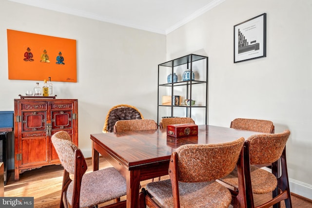 dining room with light hardwood / wood-style floors and crown molding