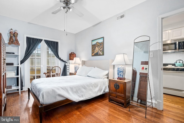 bedroom with hardwood / wood-style floors, ceiling fan, and baseboard heating