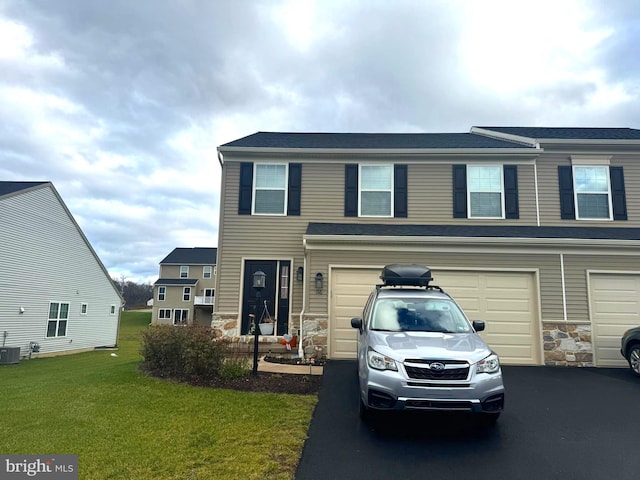 view of front of property featuring cooling unit, a front lawn, and a garage