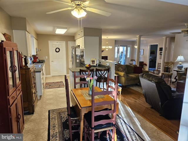 dining room featuring decorative columns, light hardwood / wood-style floors, and ceiling fan with notable chandelier