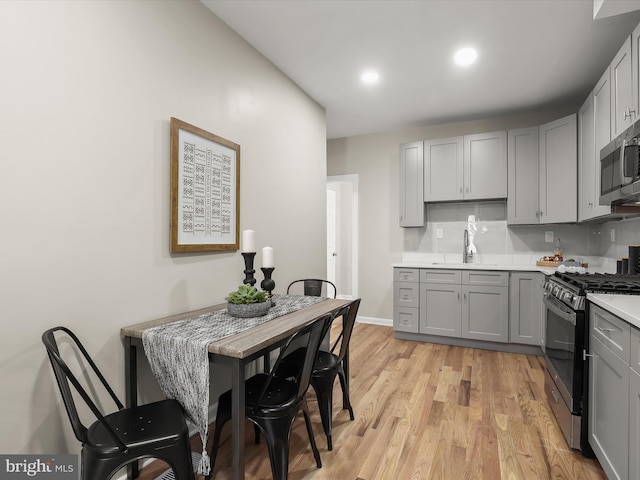 kitchen with gray cabinetry, sink, light wood-type flooring, and appliances with stainless steel finishes