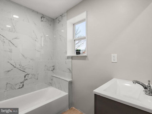 bathroom featuring tiled shower / bath and vanity