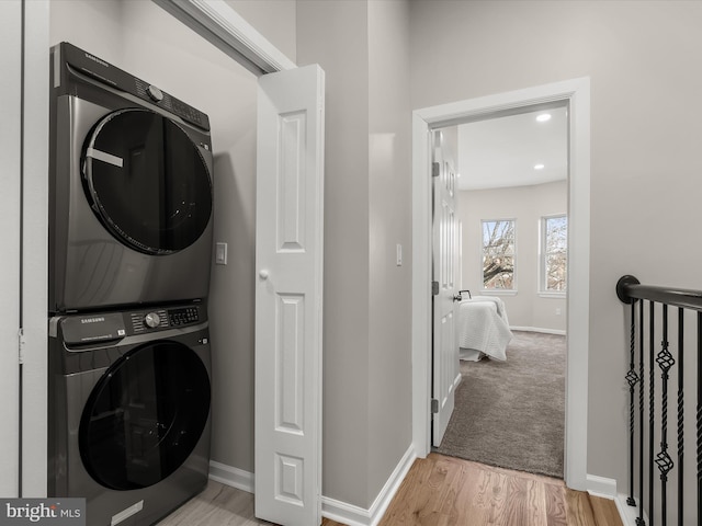 washroom featuring light hardwood / wood-style floors and stacked washer and clothes dryer