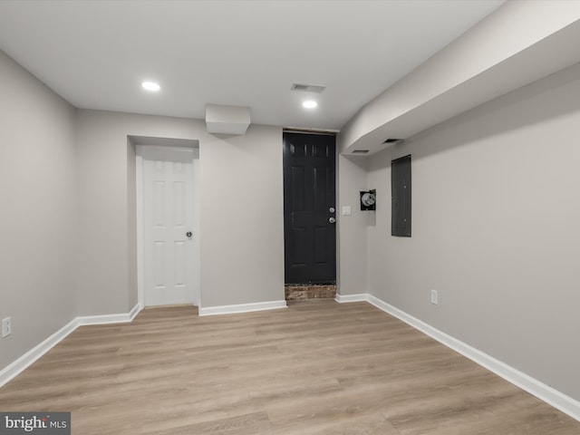 basement with electric panel and light hardwood / wood-style floors