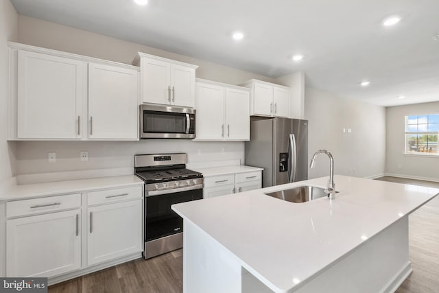 kitchen with sink, stainless steel appliances, hardwood / wood-style floors, an island with sink, and white cabinets