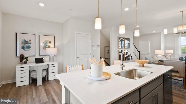 kitchen featuring decorative light fixtures, dark hardwood / wood-style floors, sink, and an island with sink