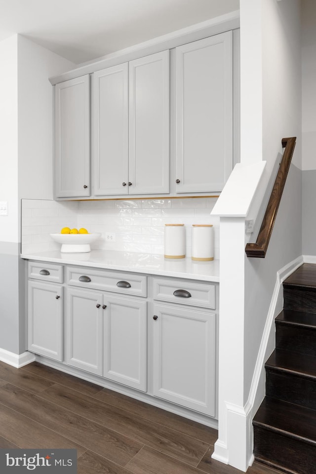 bar area with tasteful backsplash, dark wood-style floors, baseboards, and stairway