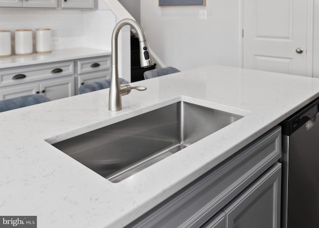 kitchen view of a sink, light stone counters, and dishwasher