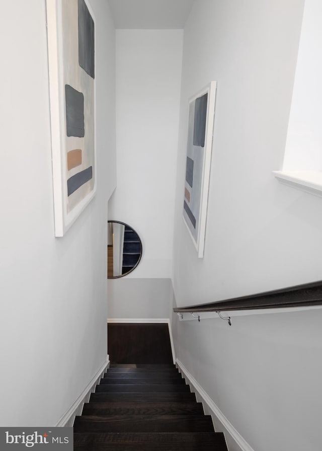 staircase featuring baseboards and wood finished floors