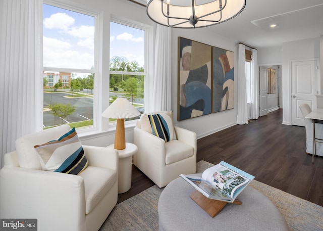 living area with healthy amount of natural light, dark wood-type flooring, a chandelier, and recessed lighting