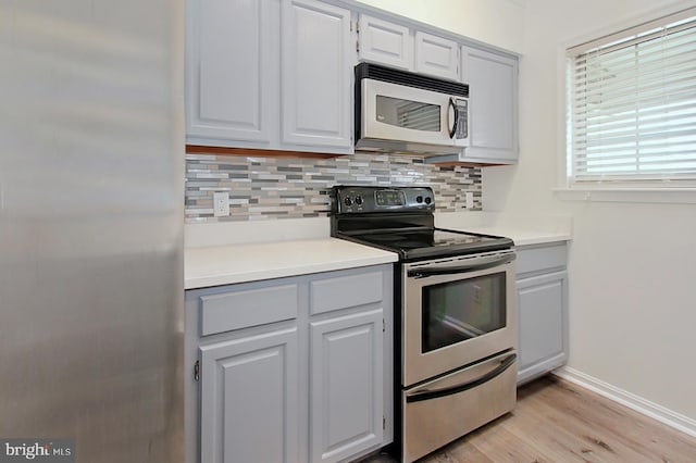 kitchen with backsplash, light hardwood / wood-style flooring, and stainless steel appliances