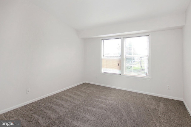 carpeted spare room featuring vaulted ceiling