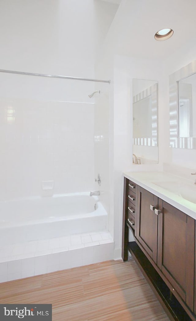 bathroom with hardwood / wood-style floors, vanity, and tiled shower / bath