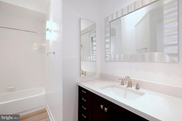 bathroom with hardwood / wood-style floors, vanity, and shower / washtub combination