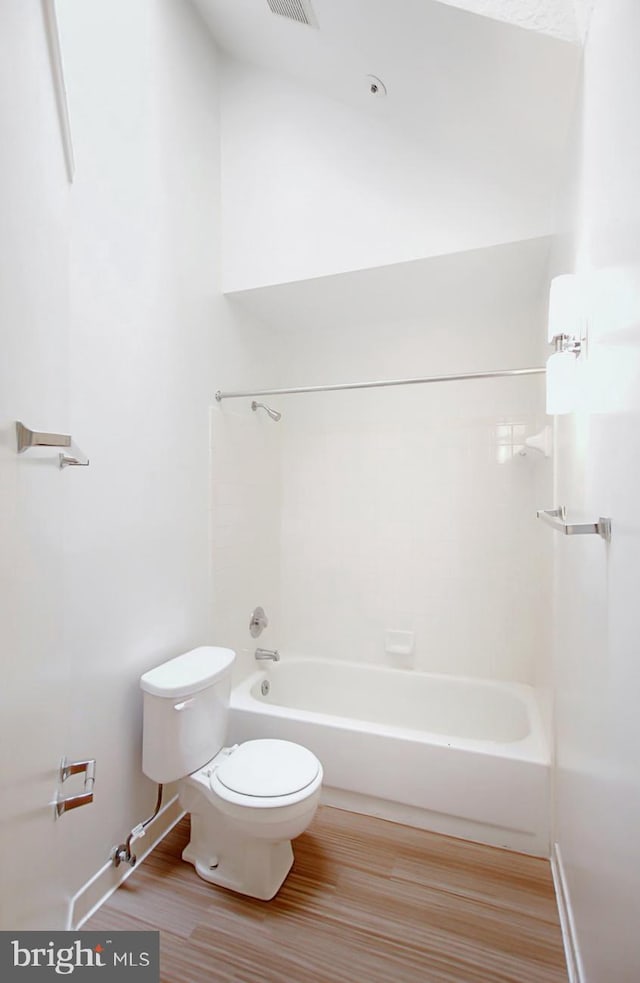 bathroom with shower / washtub combination, wood-type flooring, and toilet