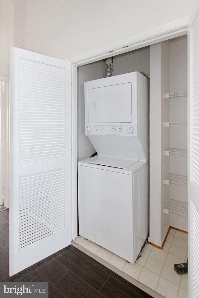 laundry area featuring wood-type flooring and stacked washer / drying machine