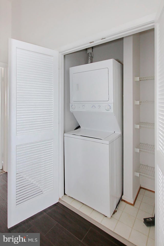 clothes washing area featuring hardwood / wood-style floors and stacked washing maching and dryer