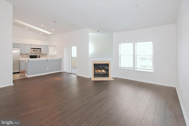 unfurnished living room featuring dark hardwood / wood-style flooring and vaulted ceiling