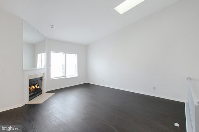 unfurnished living room with dark hardwood / wood-style flooring and a skylight