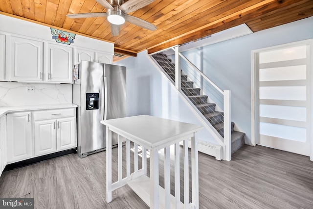 kitchen with white cabinetry, backsplash, stainless steel fridge, light hardwood / wood-style floors, and wood ceiling