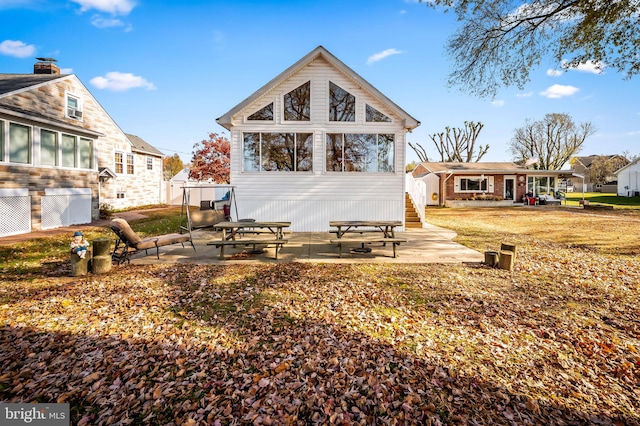 back of house with a lawn and a patio