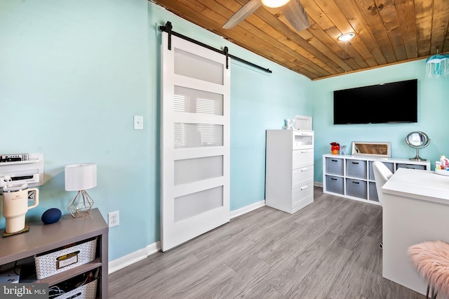 interior space with a barn door, ceiling fan, wood ceiling, and light hardwood / wood-style floors