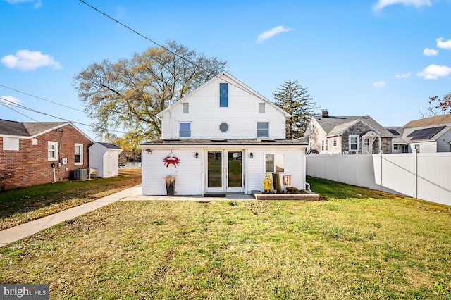 back of property with a yard, cooling unit, and a storage shed