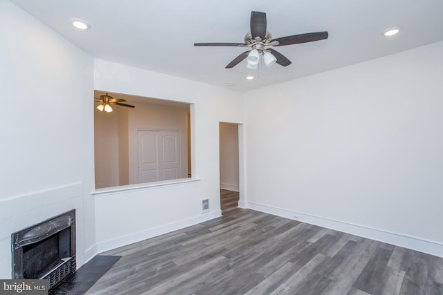 unfurnished living room with a fireplace, ceiling fan, and dark wood-type flooring