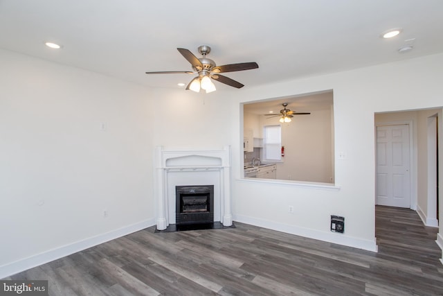 unfurnished living room with ceiling fan, dark wood-type flooring, and sink