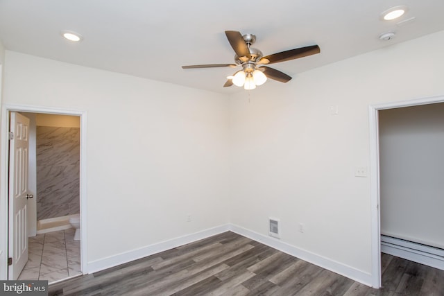 unfurnished bedroom with ceiling fan, ensuite bathroom, dark wood-type flooring, and a baseboard radiator