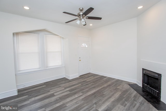 unfurnished living room with ceiling fan, a fireplace, and dark hardwood / wood-style floors