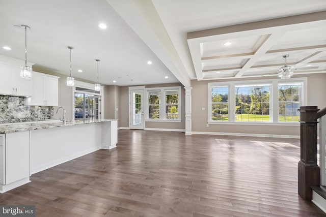 unfurnished living room featuring coffered ceiling, plenty of natural light, beamed ceiling, and dark hardwood / wood-style floors