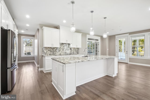 kitchen with white cabinets, stainless steel fridge, a wealth of natural light, and a kitchen island with sink