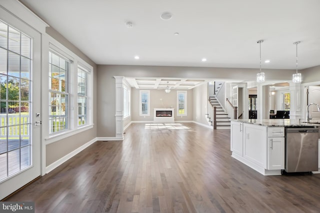 kitchen with hanging light fixtures, stainless steel dishwasher, dark hardwood / wood-style floors, light stone countertops, and white cabinetry