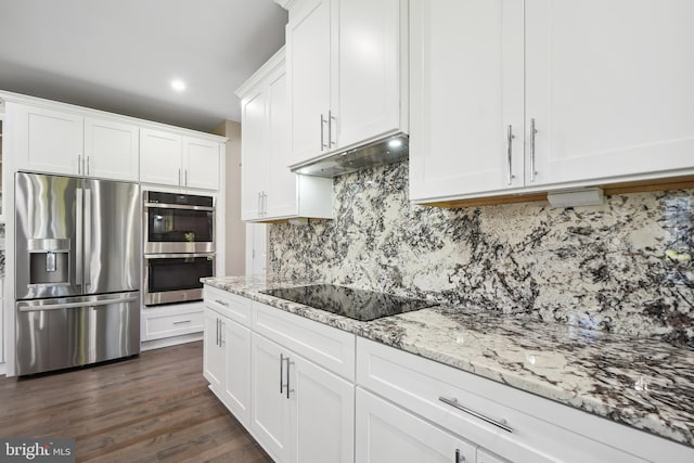 kitchen featuring white cabinets, light stone counters, appliances with stainless steel finishes, tasteful backsplash, and dark hardwood / wood-style flooring