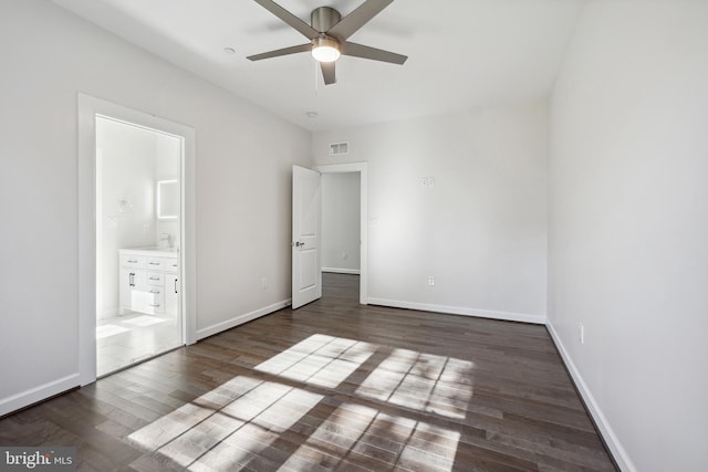 unfurnished bedroom with ensuite bath, ceiling fan, and dark wood-type flooring