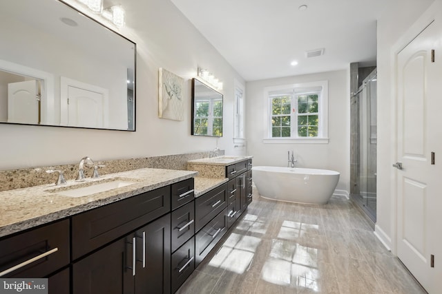 bathroom featuring plus walk in shower, wood-type flooring, and vanity