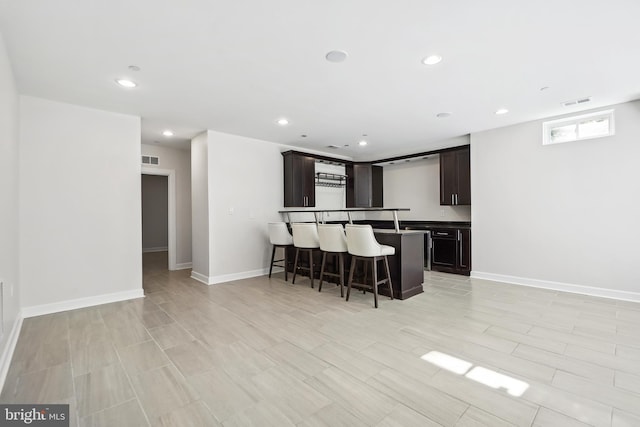 kitchen with a kitchen breakfast bar, a kitchen island, dark brown cabinetry, and light hardwood / wood-style flooring