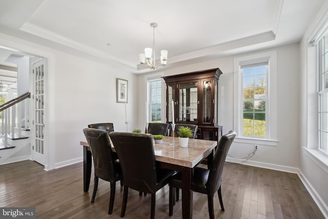 dining room featuring dark hardwood / wood-style floors, a raised ceiling, crown molding, and an inviting chandelier