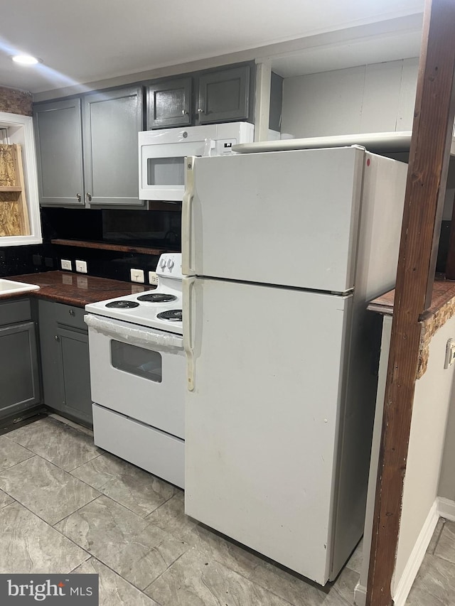 kitchen with gray cabinetry, decorative backsplash, and white appliances